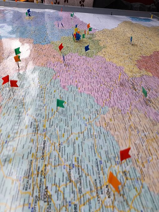 Landkarte mit mehreren farbigen Stecknadeln, die verschiedene Orte markieren.