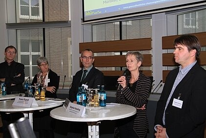 15.	Foto zeigt mehrere Diskutanten bei einer Podiumsdiskussion