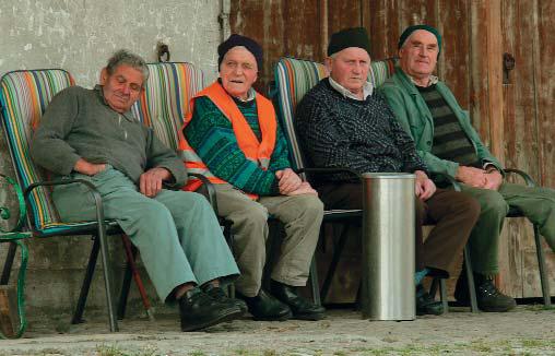 eine Gruppe von älteren Menschen, die auf Stühlen vor einer Hauswand sitzen